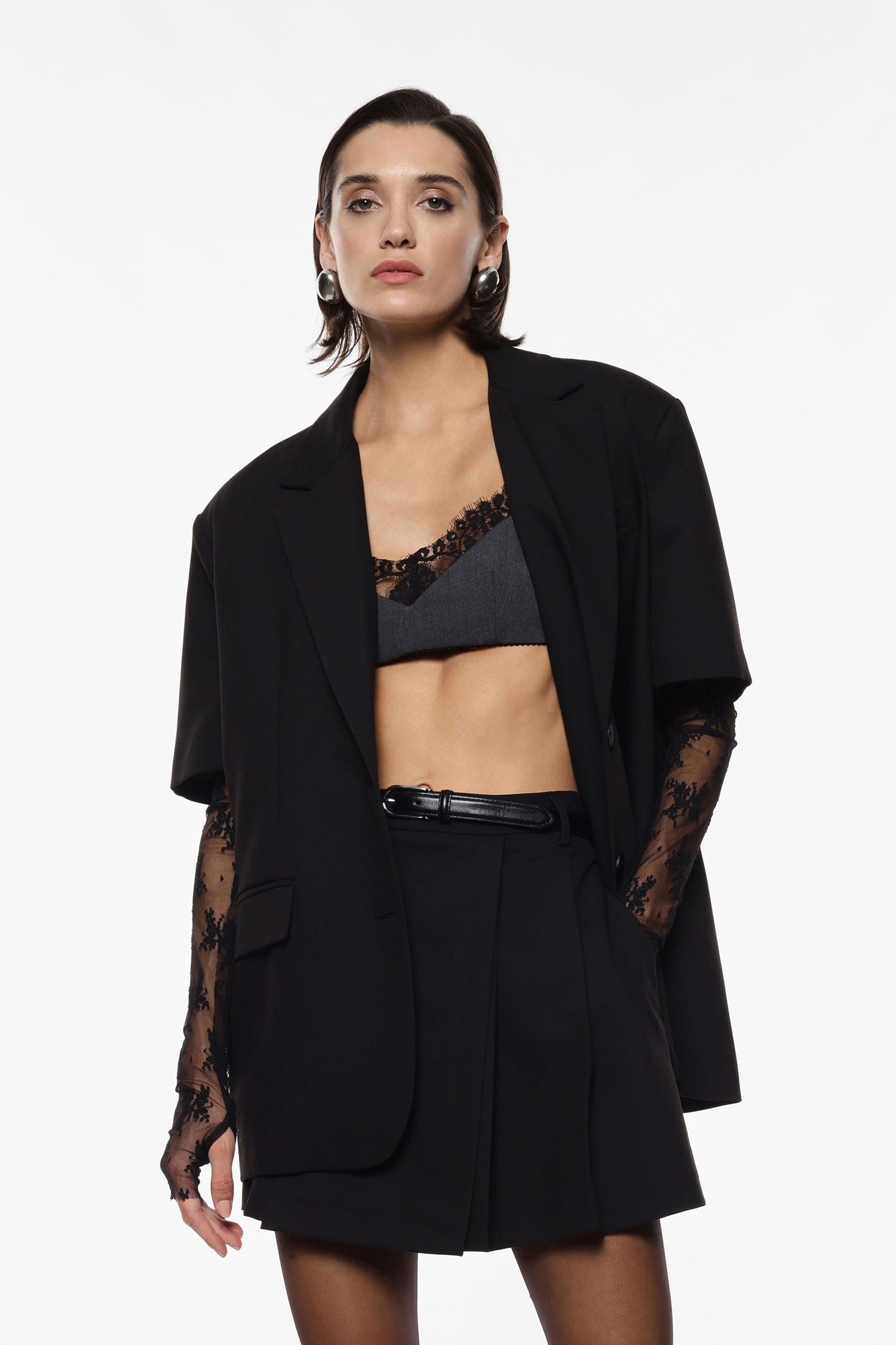 Woman wearing a black outfit with sheer sleeves on a white background